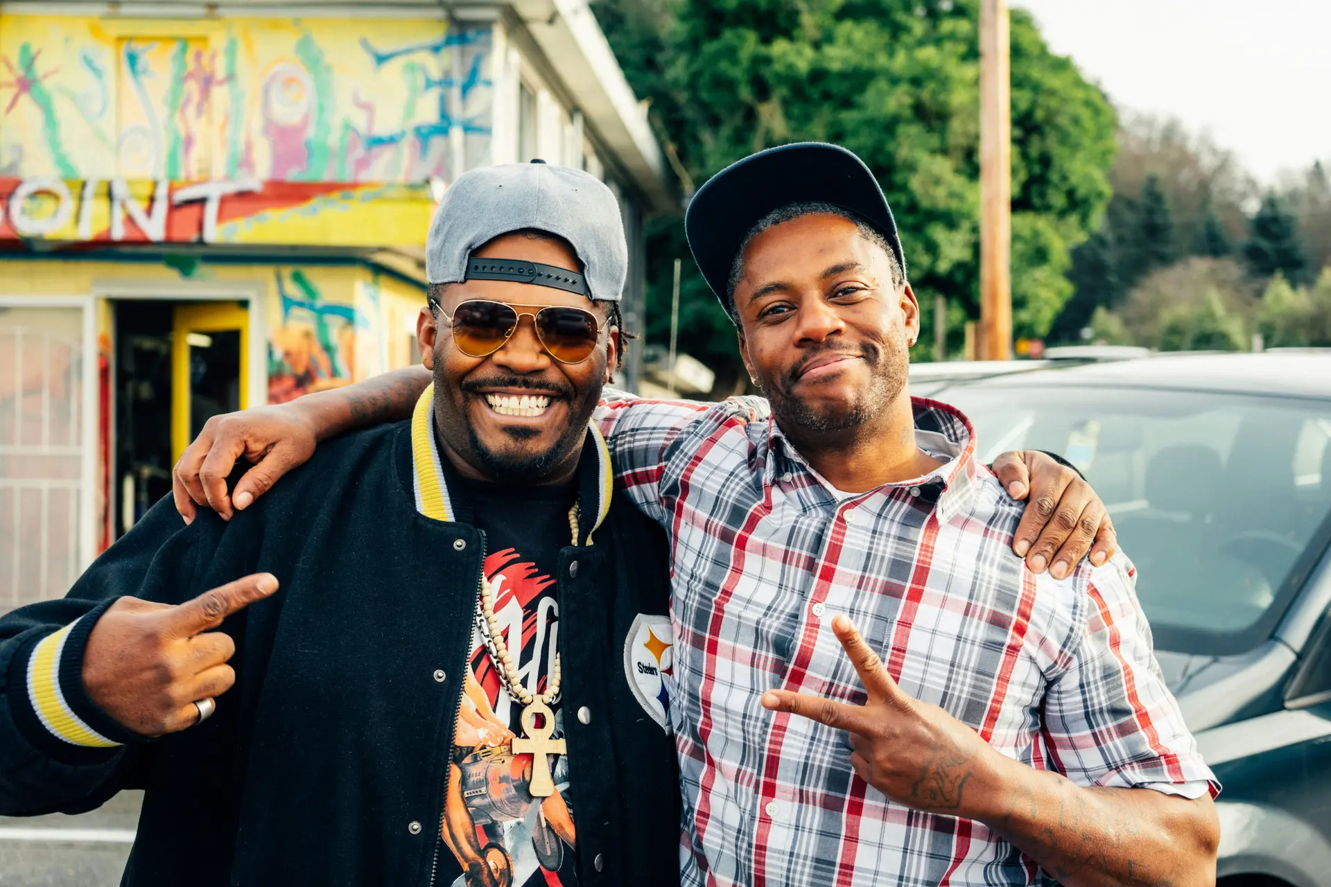 Two friends with their arms around each other, one making a peace sign.